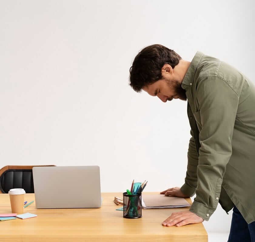Man standing at desk with face down