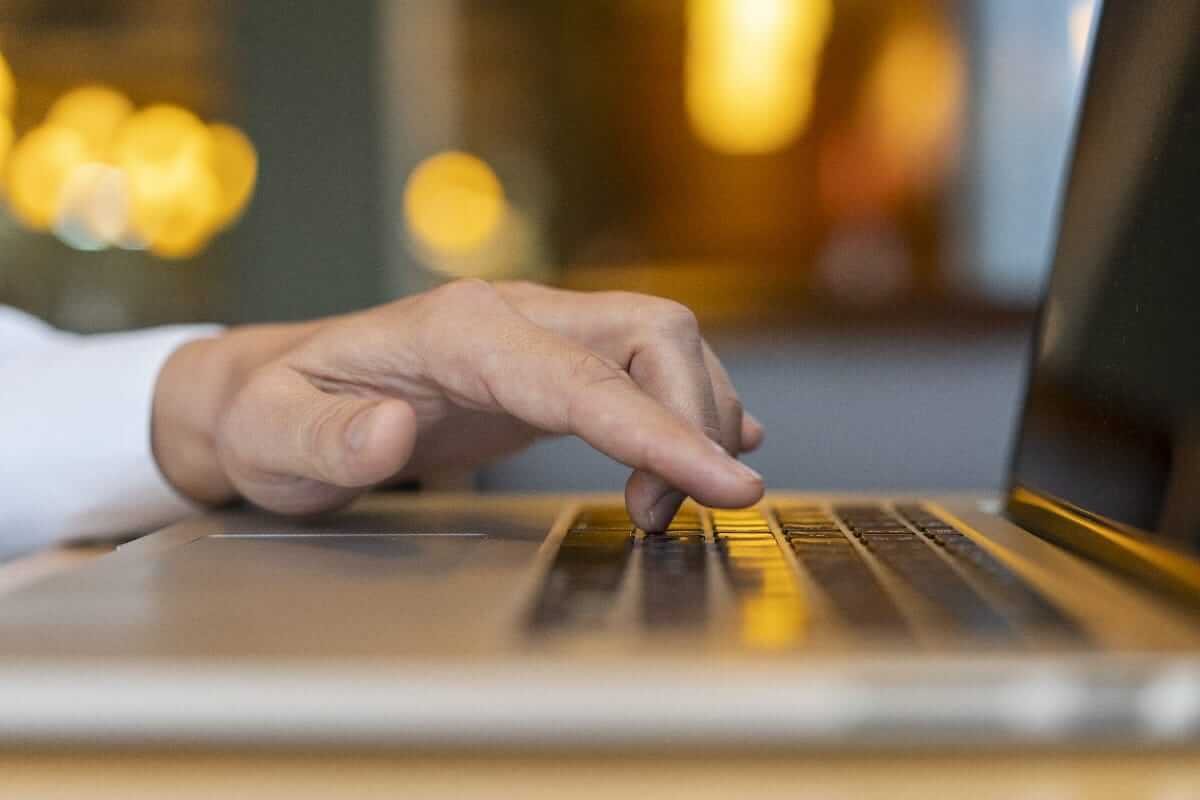 Man's hands typing on a laptop, wrists compressed against surface